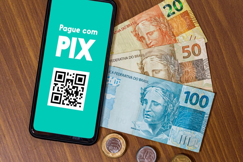 Pix on smartphone screen with multiple coins around. Pix is the new payment and transfer system of the Brazilian and Brazilian government.